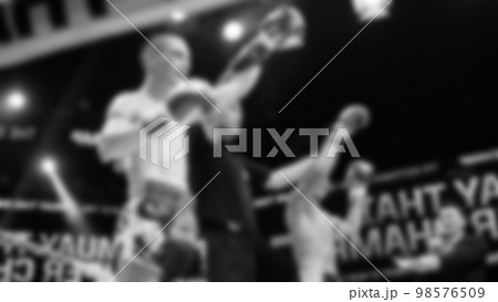 Blurred images black and white photo style of Thai boxing or Muay Thai or Kickboxing which local and foriegn boxer are fighting on the ring at indoor stage as martial art sport. Muay Thai Kick boxing 98576509