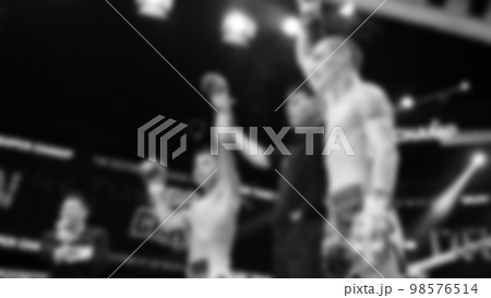 Blurred images black and white photo style of Thai boxing or Muay Thai or Kickboxing which local and foriegn boxer are fighting on the ring at indoor stage as martial art sport. Muay Thai Kick boxing 98576514