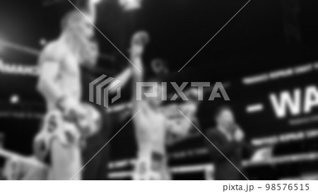 Blurred images black and white photo style of Thai boxing or Muay Thai or Kickboxing which local and foriegn boxer are fighting on the ring at indoor stage as martial art sport. Muay Thai Kick boxing 98576515