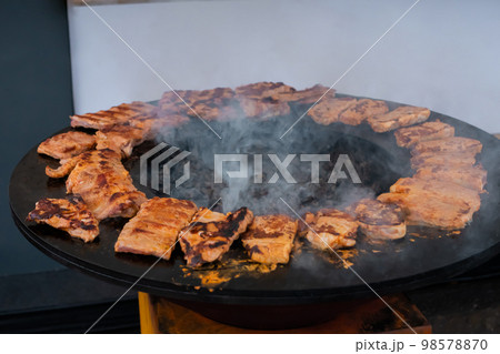 Process of cooking meat steaks on round brazier - close up Process of cooking meat steaks on round brazier - close up 98578870