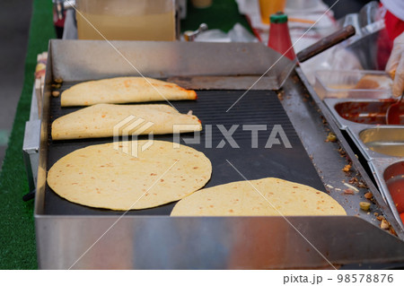 Preparing fresh quesadilla on black grill at summer local food market Preparing fresh quesadilla on black grill at summer local food market 98578876