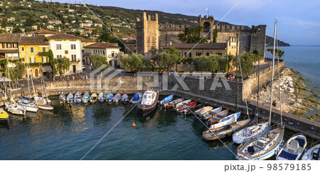 Scenic places of beautiful lake Lago di Garda. aerial view of charming village Torri del Benaco over sunset . Italy, Verona province 98579185