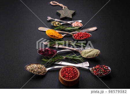 Composition consisting of a variation of spices in metal spoons laid out in the shape of a Christmas tree 98579382