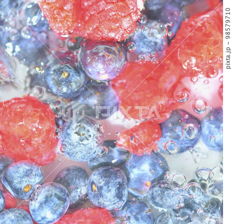 Water with fresh berries, close-up. Close-up view of the blueberries and raspberries in water background. Texture of bilberries and raspberries with macro bubbles on the glass wall. Flat design, top Water with fresh berries, close-up. Close-up view of the blueberries and raspberries in water background. Texture of bilberries and raspberries with macro bubbles on the glass wall. Flat design, top 98579710