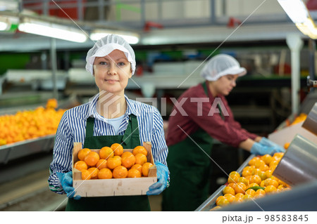 Smiling woman sorter with box of tangerines at fruit factory 98583845