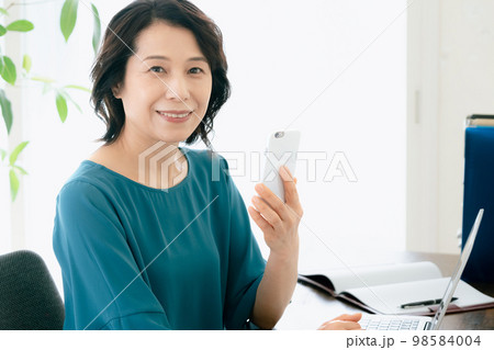 パソコンとスマホで検索するミドル女性 98584004