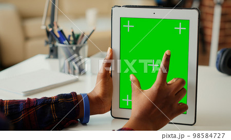 Female entrepreneur vertically holding isolated greenscreen on digital tablet, looking at blank chroma key display with mockup background. Using copy space on portable device. Close up. 98584727