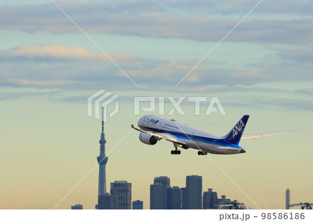 朝日を浴びて離陸する旅客機　離陸上昇するジェット機　東京スカイツリーを背景に離陸するANA機 98586186