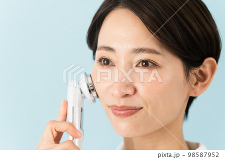 ナース服を着て美顔器の説明をしている若い女性　美容イメージ	 98587952