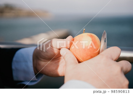 Man apple park. Hipster millennial man in a tie and jacket takes a bite out of an apple while sitting on a park bench in slow motion Young business people eating golden apples in lunch time. 98590813