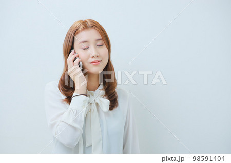電話中に目を閉じた若い女性 電話中に目を閉じた若い女性 98591404