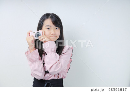 デジカメを構えるカメラ目線の女子 98591617