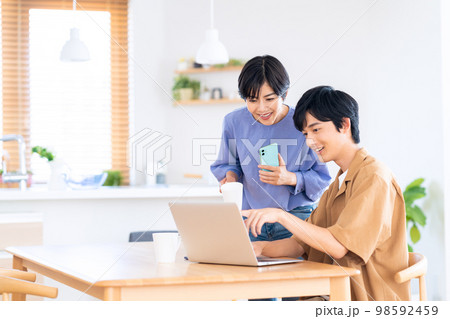夫婦 カップル パソコン スマホ テレワーク 家族 ライフスタイル リビング 夫婦 カップル パソコン スマホ テレワーク 家族 ライフスタイル リビング 98592459
