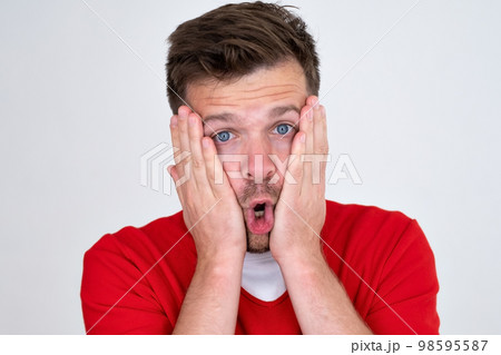 Man being afraid and shocked, surprise and amazed expression with hands on face Man being afraid and shocked, surprise and amazed expression with hands on face 98595587