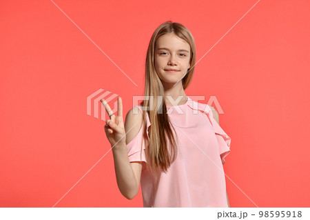 Studio portrait of a beautiful girl blonde teenager in a rosy t-shirt posing on pink background. Studio portrait of a beautiful girl blonde teenager in a rosy t-shirt posing on pink background. 98595918