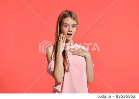 Studio portrait of a beautiful girl blonde teenager in a rosy t-shirt posing on pink background. 98595962