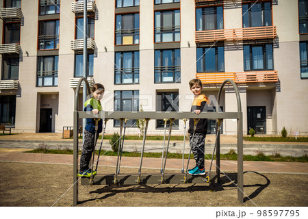 Two young boy active little child playing climbing at spring metal playground his hand to exercise at outdoor. Warm sunny day. Friendship concept Two young boy active little child playing climbing at spring metal playground his hand to exercise at outdoor. Warm sunny day. Friendship concept 98597795