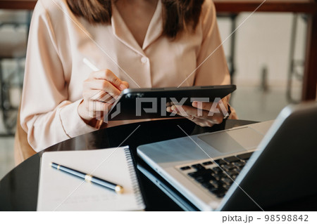 business documents on office table with smart phone and digital tablet and graph financial and woman working at office. 98598842