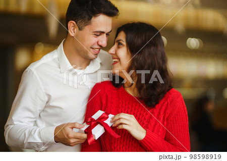 Young man gives his beloved a present and closes her eyes with a hand. Valentine's Day. Women's Day. Young man gives his beloved a present and closes her eyes with a hand. Valentine's Day. Women's Day. 98598919