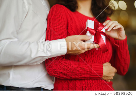 Young man gives his beloved a present and closes her eyes with a hand. Valentine's Day. Women's Day. Young man gives his beloved a present and closes her eyes with a hand. Valentine's Day. Women's Day. 98598920