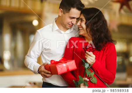 A young man gives his beloved a present and closes her eyes with a hand. Valentine's Day. A young man gives his beloved a present and closes her eyes with a hand. Valentine's Day. 98598938