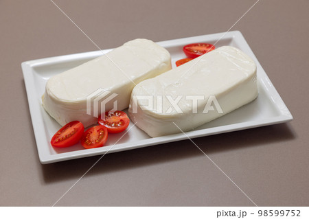 Pieces of Italian cow mozzarella cheese for pizza on a white rectangular plate (selective focus) 98599752
