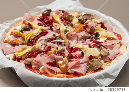 Uncooked homemade Italian pizza capricciosa with classic ingredients ready for baking 98599753