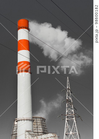 The pipe of the industrial plant emits toxic grey smoke into the atmosphere sky and air. Pollution of the environment and ecology. Thermal power plant power lines high voltage 98600182