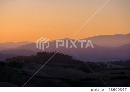 Sunrise in the typical Tuscan hills with cypresses, vineyards and house, Tuscany, Volterra, Italy 98600347