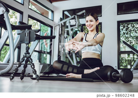 Asian woman training exercise on yoga mat and using mobile phone. Female sport blogger recording video by smart phone. Exercise online training class at gym indoors. Asian woman training exercise on yoga mat and using mobile phone. Female sport blogger recording video by smart phone. Exercise online training class at gym indoors. 98602248