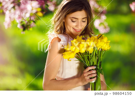 Spring Style. Beautiful Young Brunette Woman In Nice Spring Dress With A Bouquet Of Tulips. 98604150