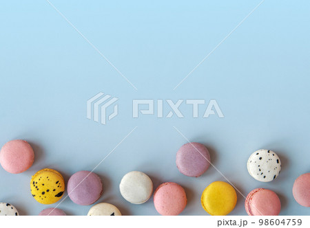 Many different macaroons on blue background with copy space. Pink, white and violet French cookies. Strawberry, black currant and blueberry vanilla meringue dessert 98604759