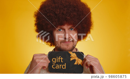 Young happy man showing pointing gift discount certificate voucher coupon for store holidays sale 98605875