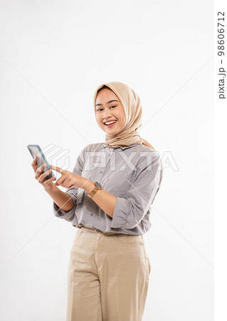 a young woman with hijab standing and pointing on her phone 98606712