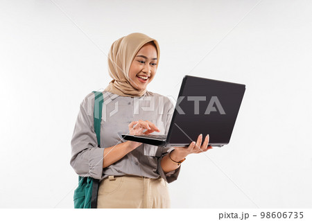 a female student with hijab smiling while opened the laptop 98606735