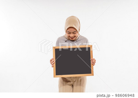 a woman with hijab showing the blackboard in front of her body 98606948