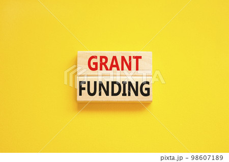 Grant funding symbol. Concept words Grant funding on wooden blocks. Beautiful yellow table yellow background. Business and grant funding concept. Copy space. 98607189