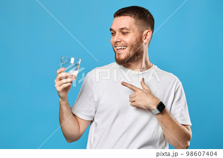 happy handsome man in white t-shirt showing drinking glass of water 98607404