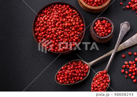 Spice, allspice peas of red or pink color in a wooden bowl 98608243
