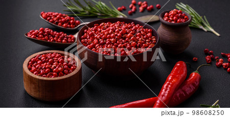 Spice, allspice peas of red or pink color in a wooden bowl 98608250