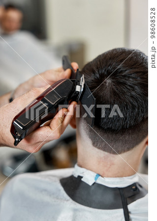 Barber shaving caucasian man in barber shop. 98608528