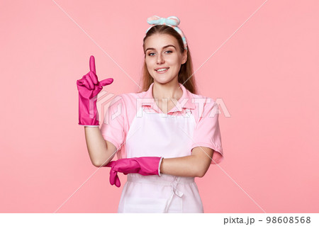 woman in gloves and apron holding index finger up with new idea woman in gloves and apron holding index finger up with new idea 98608568