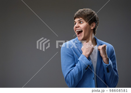 very excited young man showing victory gesture holding fists raising 98608581