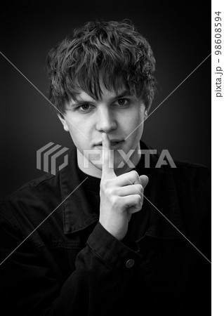 handsome man asking to be quiet with finger on lips. handsome man asking to be quiet with finger on lips. 98608594