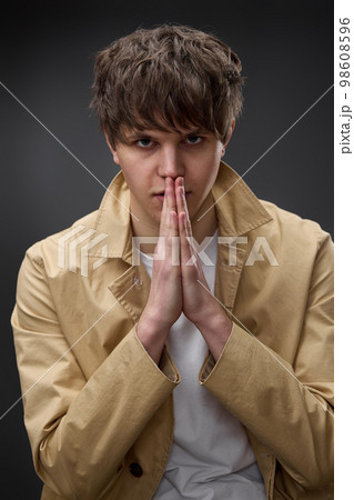young man in coat holding hands in pray young man in coat holding hands in pray 98608596