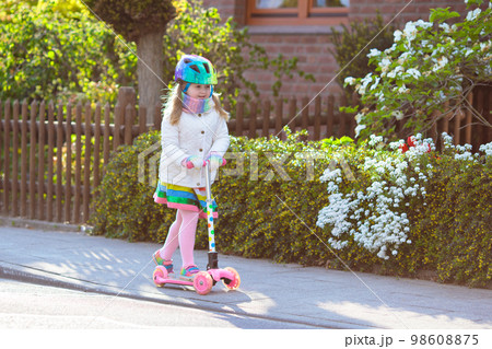 Child riding schooter on way to school Child riding schooter on way to school 98608875