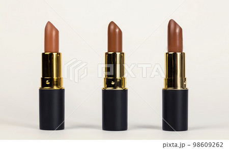 Lipsticks for lips. Three brown lipsticks of different shades on a white background. Beauty concept. Lipsticks for lips. Three brown lipsticks of different shades on a white background. Beauty concept. 98609262