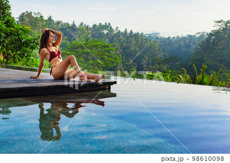 Young woman in swimming pool with tropical jungle view 98610098
