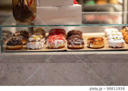 Glass showcase with different delicious glazed donuts Glass showcase with different delicious glazed donuts 98611936