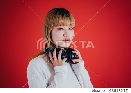 ヘッドホンを首にかける女性 98613257